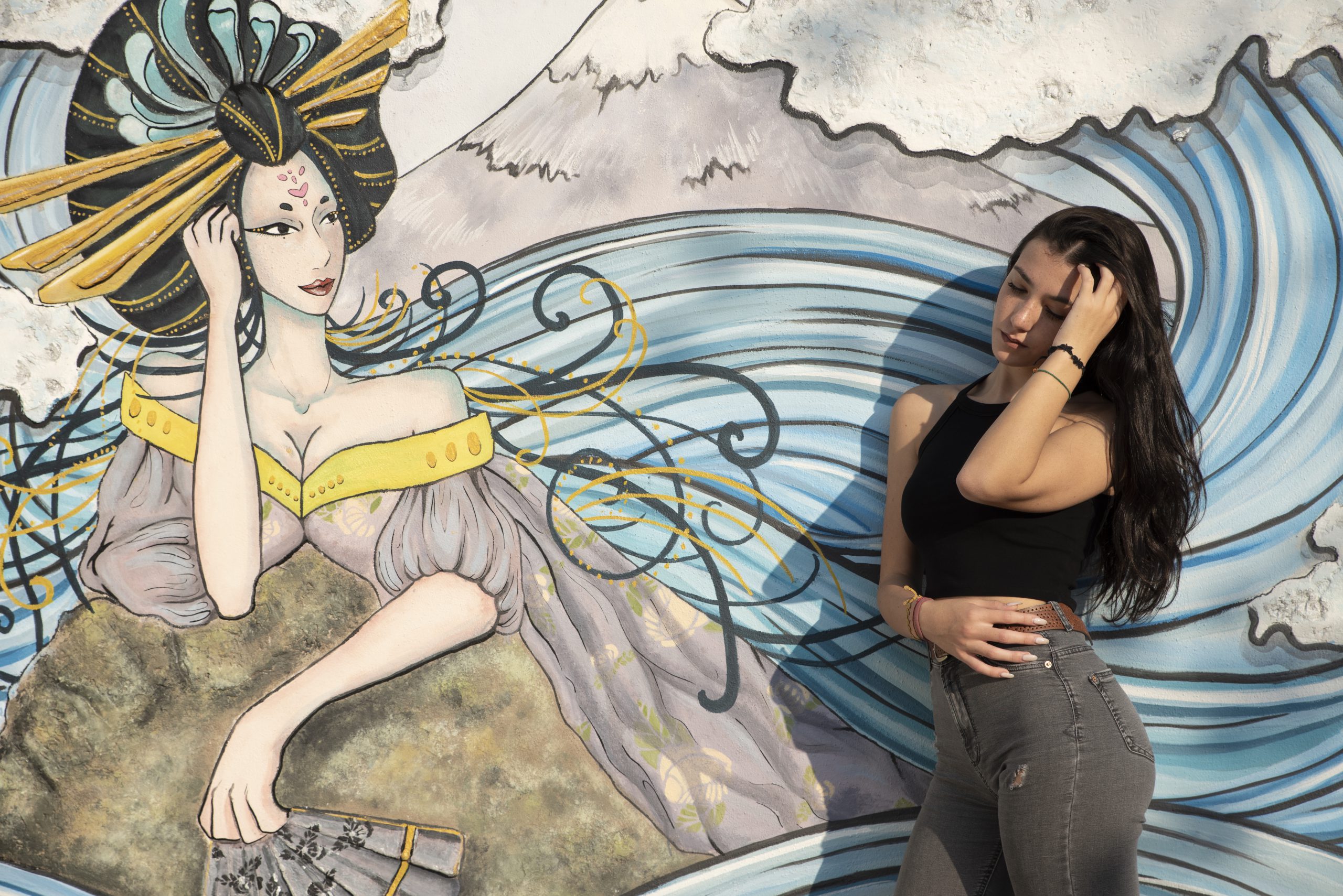 Una giovane modella che mima una donna giapponese disegnata su un murales.