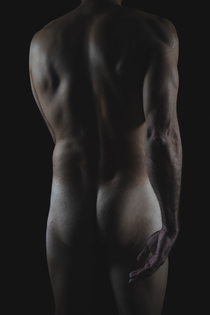 Hands - Il corpo a zone: un uomo nudo di spalle in penombra